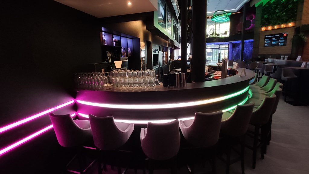 Runde Bartheke im Kino Gronau. Im oberen Drittel und ca. auf der halben Höhe sind LED-Beleuchtungsbänder mit Farbwechsel in die Theke eingelassen.